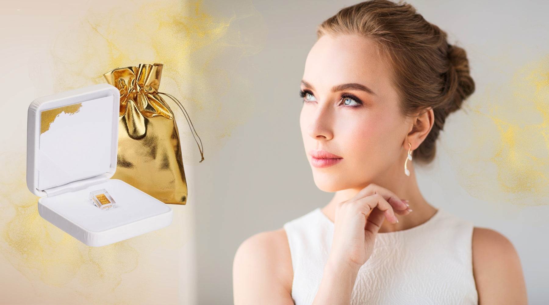 Weißes Etui mit Goldbarren und goldenem Geschenkbeutel neben eleganter Frau in Weiß.