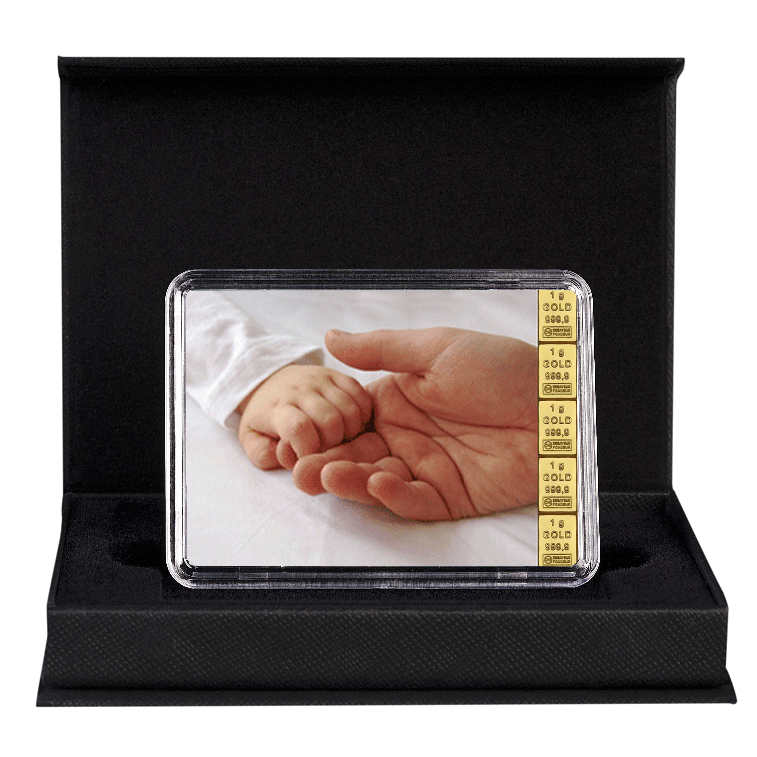 Schwarze Geschenkbox mit einem Etui, das eine Goldtafel mit Motiv einer Babyhand in einer Erwachsenenhand zeigt – ein edles Geschenk zur Geburt.